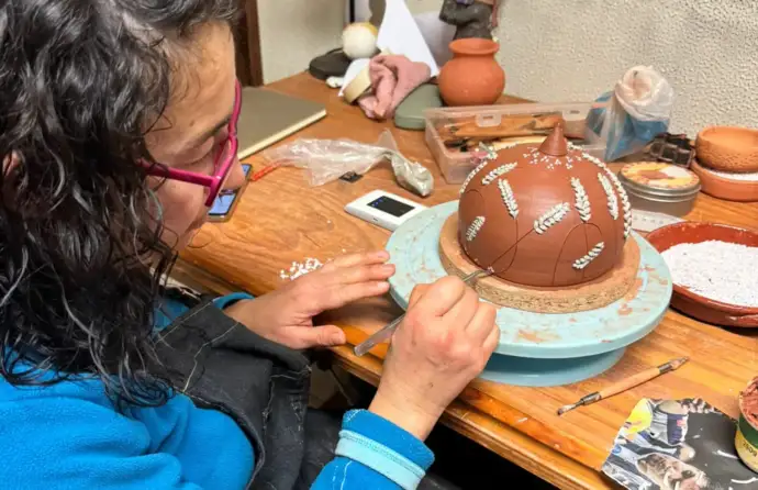 Oleira a trabalhar o barro com a colagem de pedras de quartzo para decoração